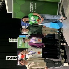 a group of five people stand in front of a University of Alberta banner