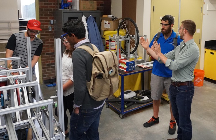 Future Energy Systems HQP Jason Michaud and David Miller explaining Stirling engine operation to visitors.