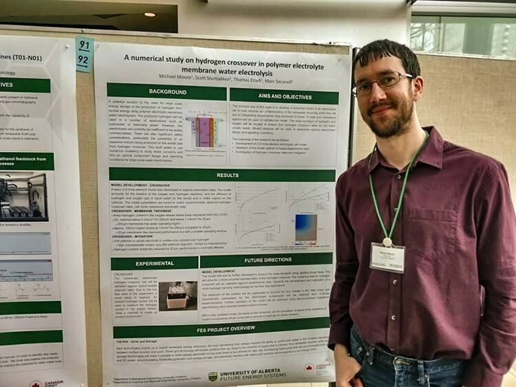 Michael stands in front of his research poster