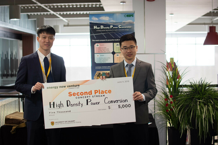 Zhongyi and colleague stand with their prize for their technology at a competition.